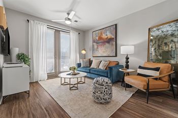 A living room with a blue couch, a patterned ottoman, and a painting on the wall at 1010 Dilworth Apartments, Charlotte, NC